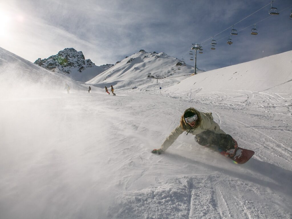 A group of snowboarders going fast down the mountain.