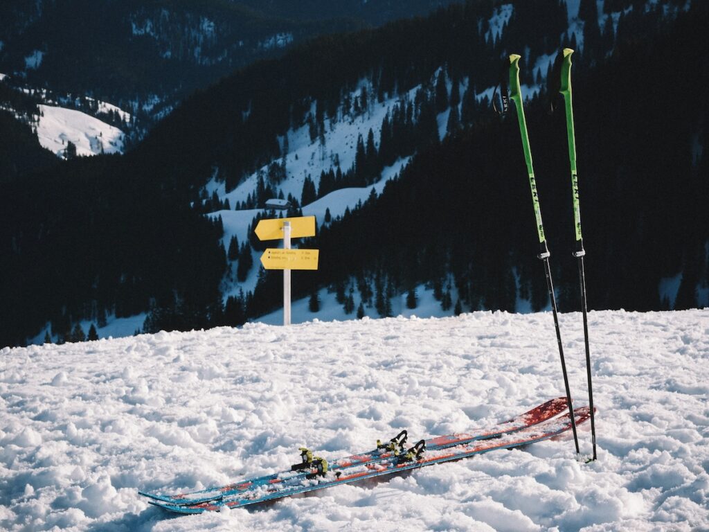 Skis and poles sitting on a ski slope. 