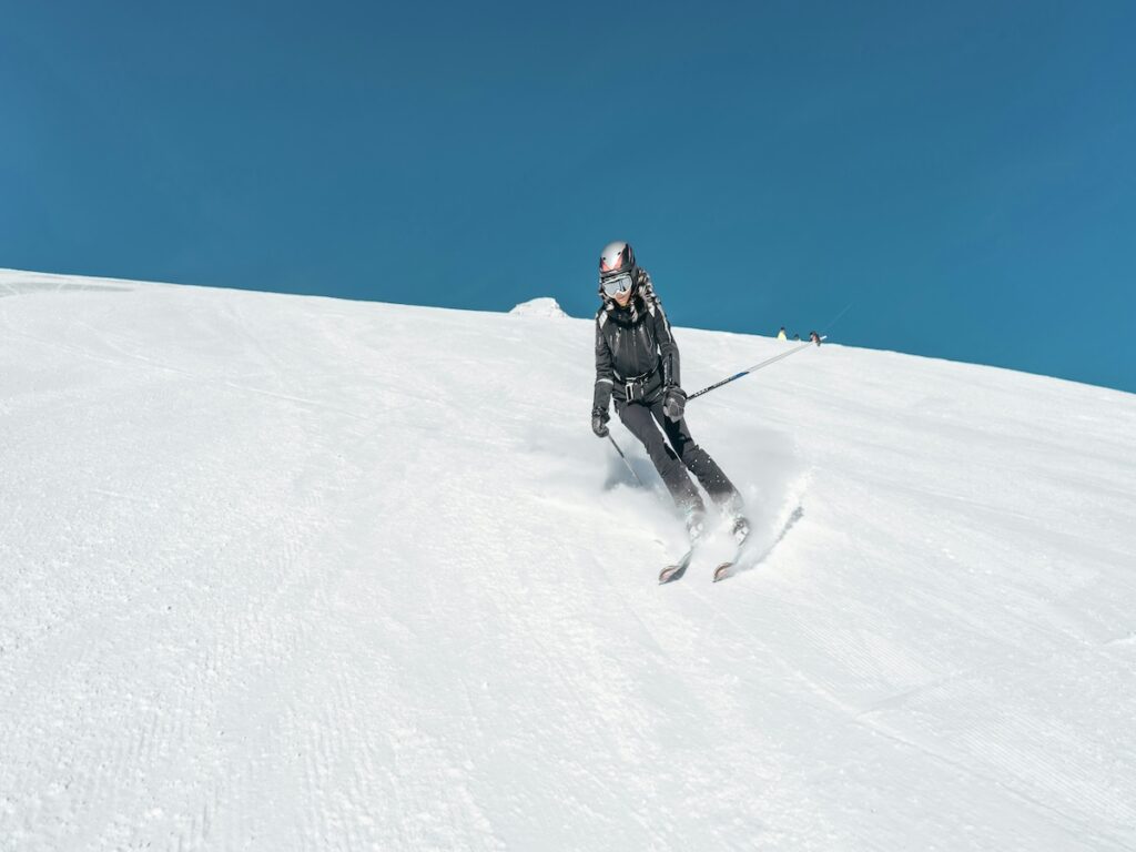 A skier going down the mountain with blue skies above.