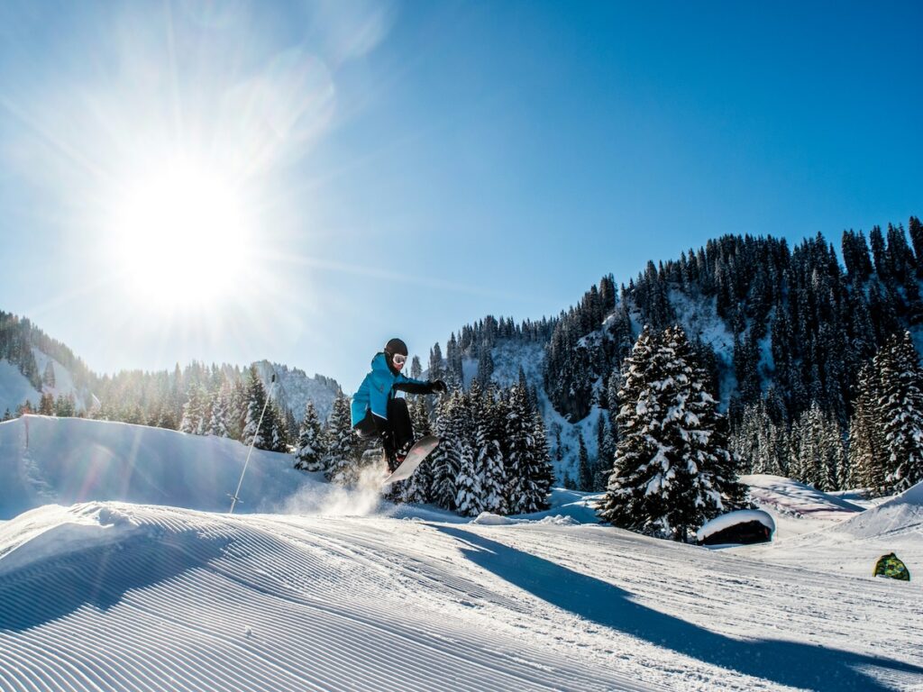 A snowboarder jumping on the slope during a bluebird day.