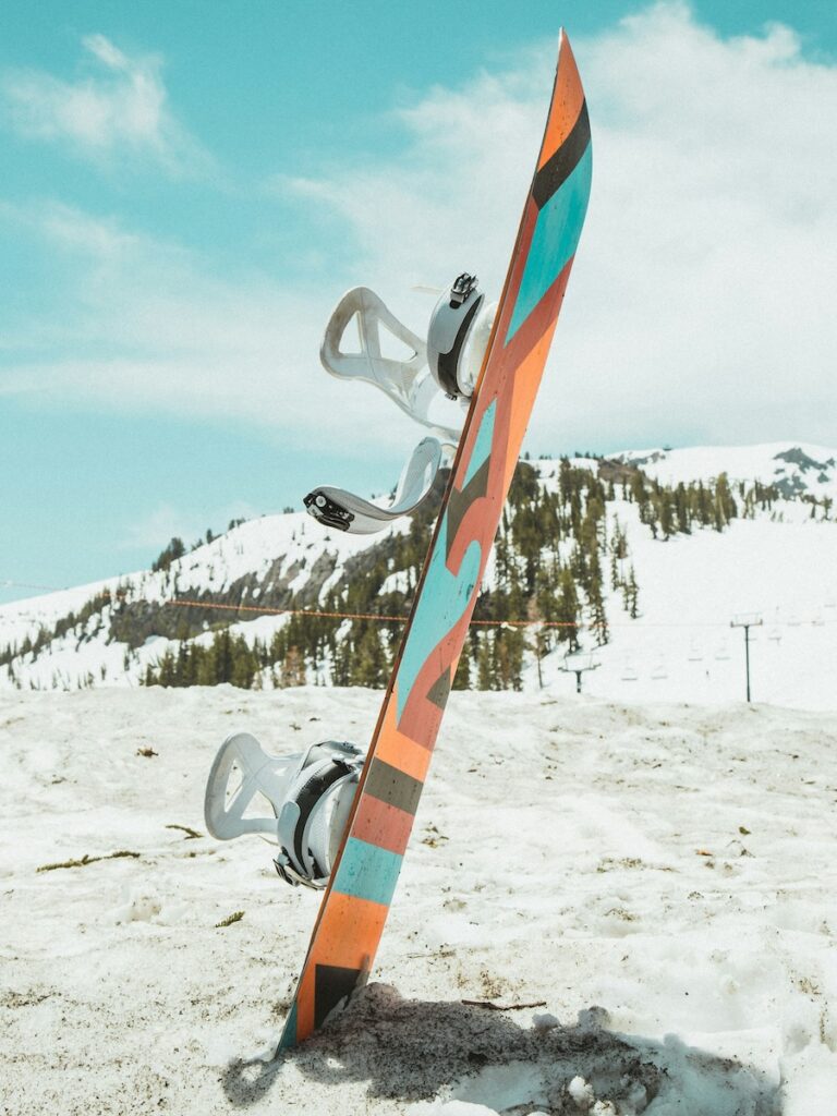 A colorful snowboard standing in the snow.