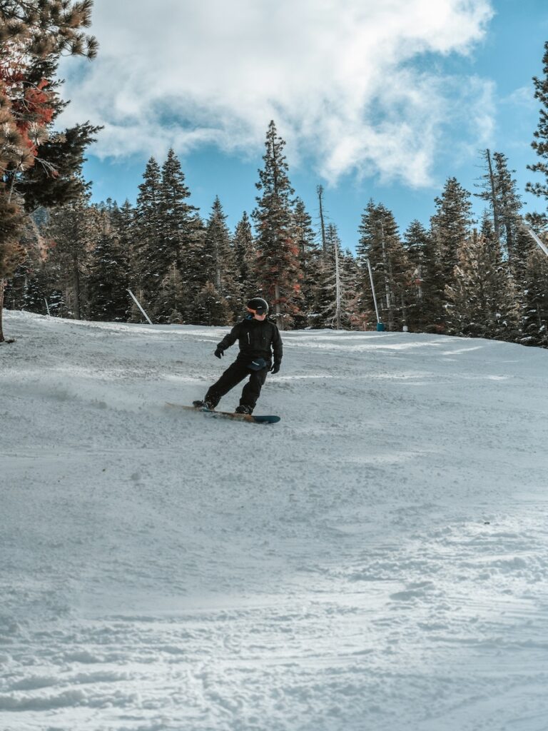 A snowboarder leisurely going down the mountain.