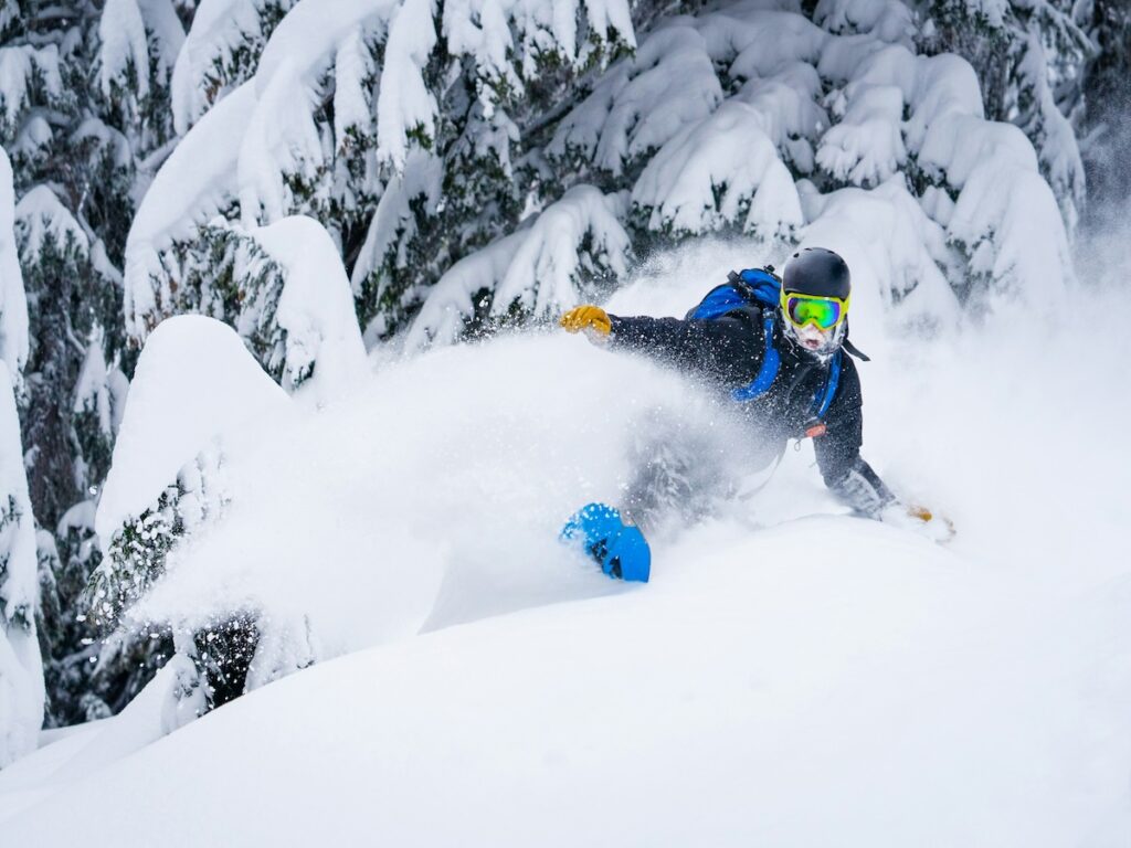 A snowboarder shredding through fresh powder.