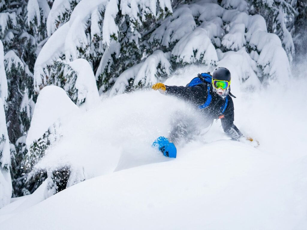 A snowboarder spraying snow in deep powder.