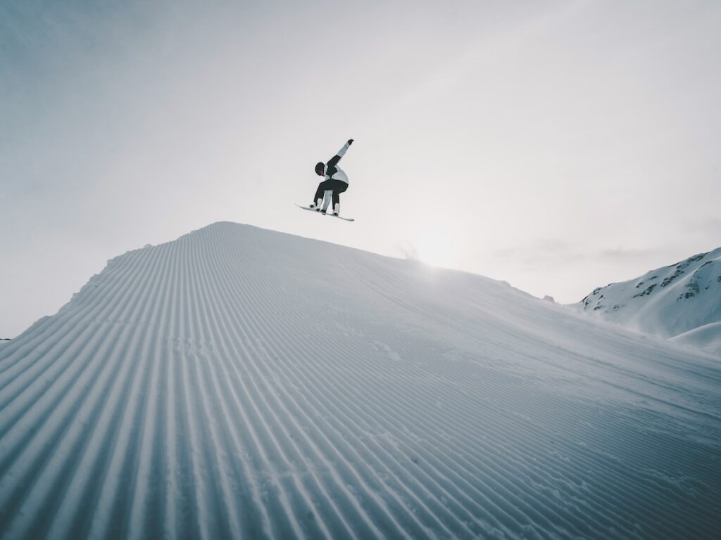 A snowboarder jumping on a groomed run.