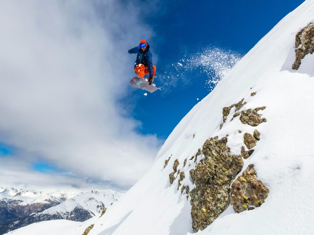 A snowboarder jumping over rocks.
