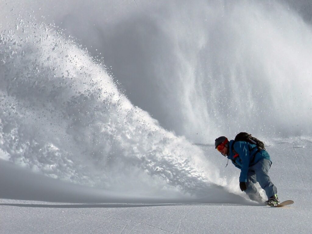 A snowboarder spraying snow.