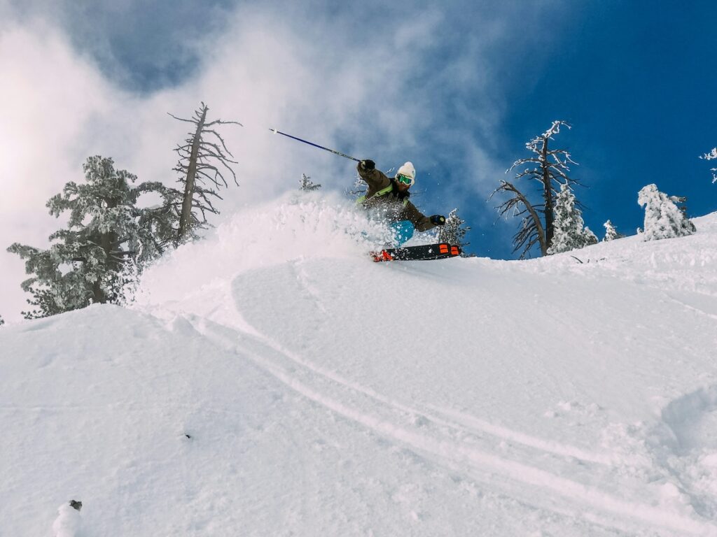 A skier spraying snow as they go down a steep slope.
