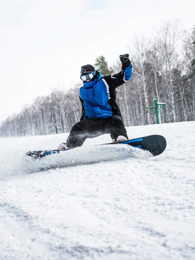 A snowboarder spraying snow while wearing a royal blue jacket.