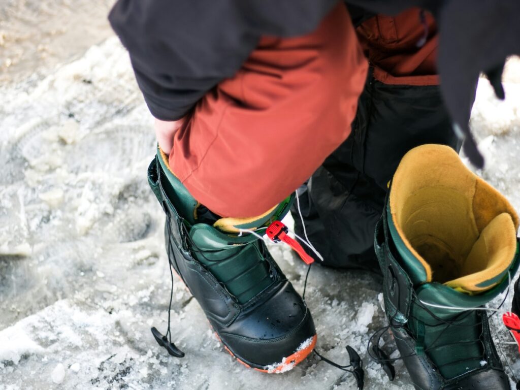 A person putting on their snowboard boots.