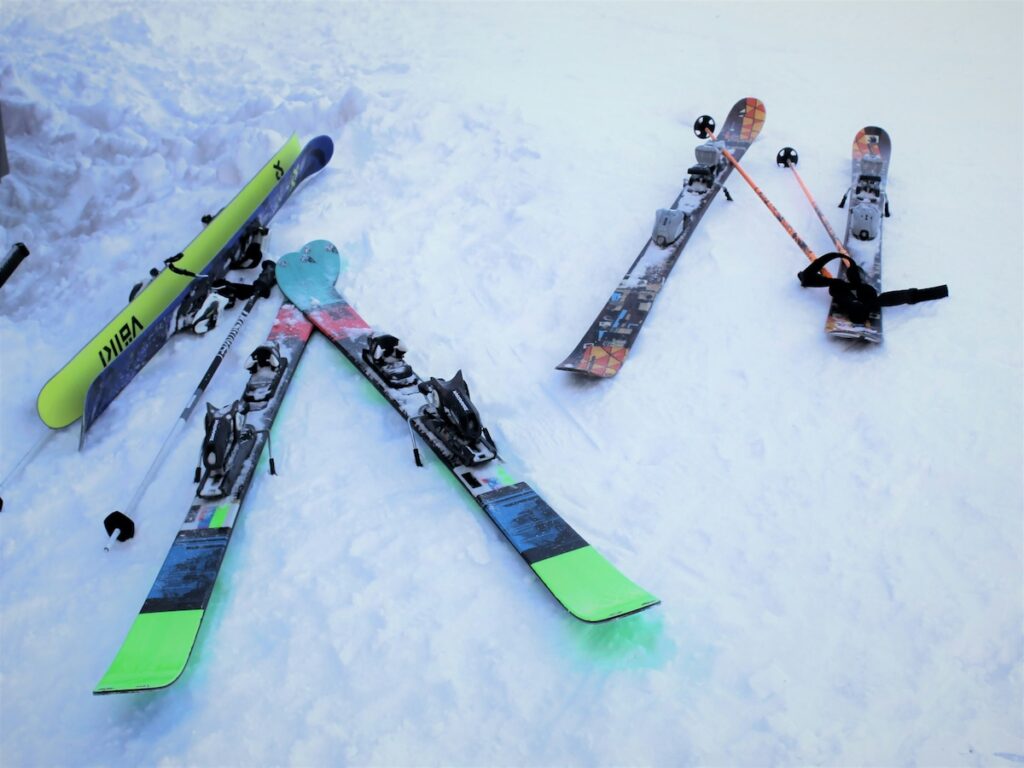 Three pairs of skis and some ski poles resting on snow.