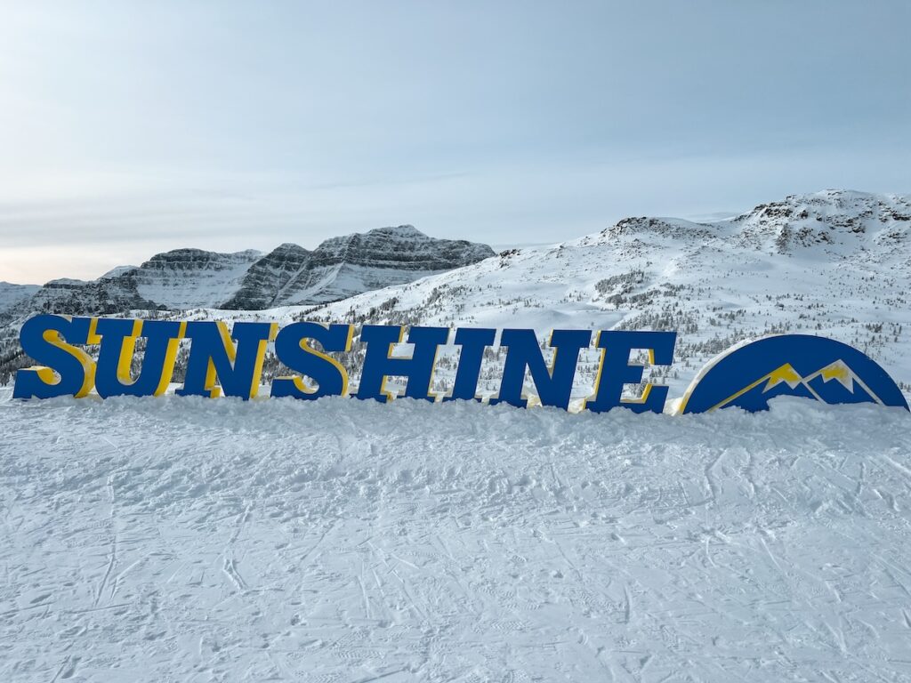 Banff Sunshine sign in Canada surrounded by mountains and snow.