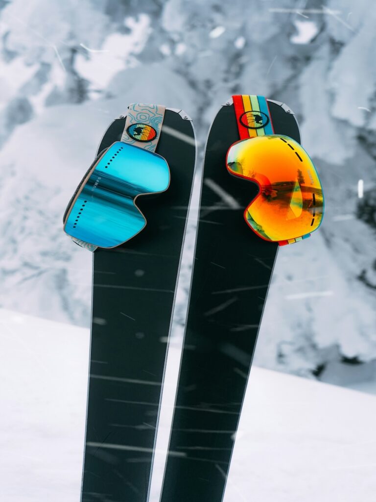 A pair of skis holding two goggles.