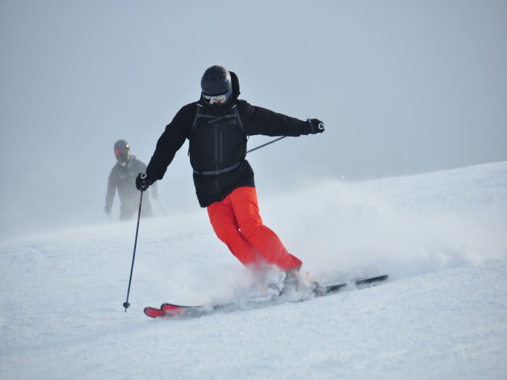 A skier going fast down the mountain with bright red pants on.