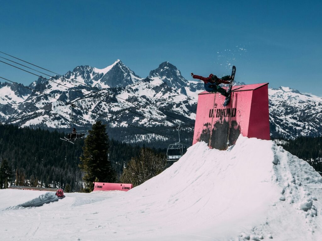 A snowboarder doing a trick with mountains in the background.