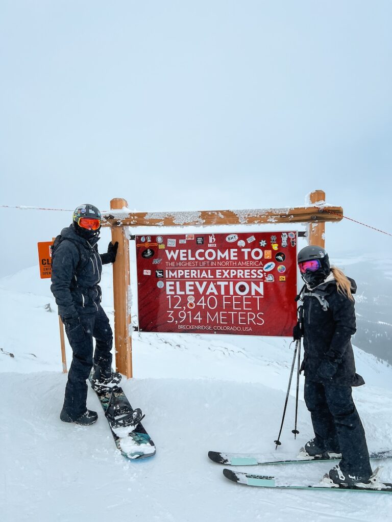 Abby and Sam smiling with the highest lift in North America sign.