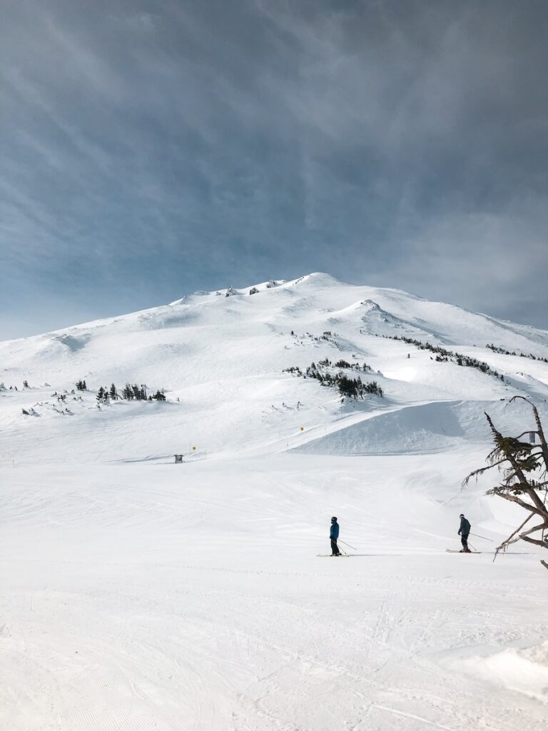 Mountain views of Mt Bachelor with skiers going across the mountain.