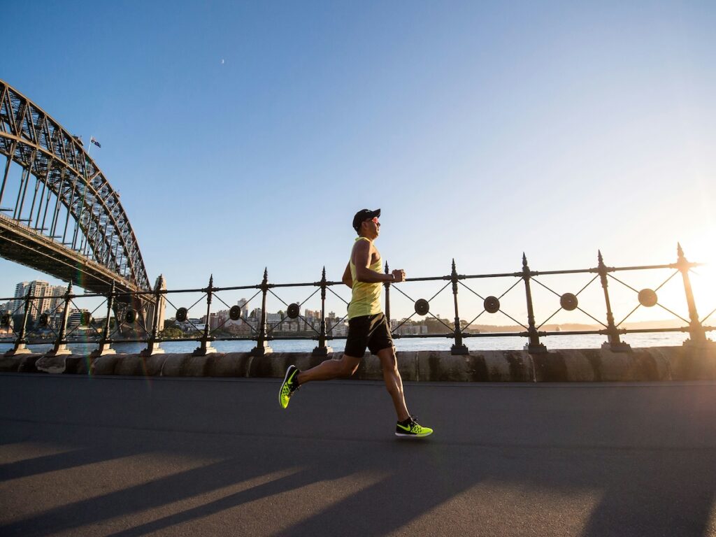 A man running outside past a bridge.