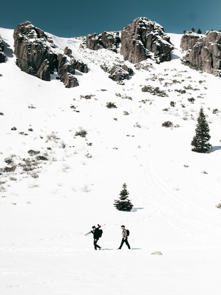 Two skiers carrying their equipment through the snow.