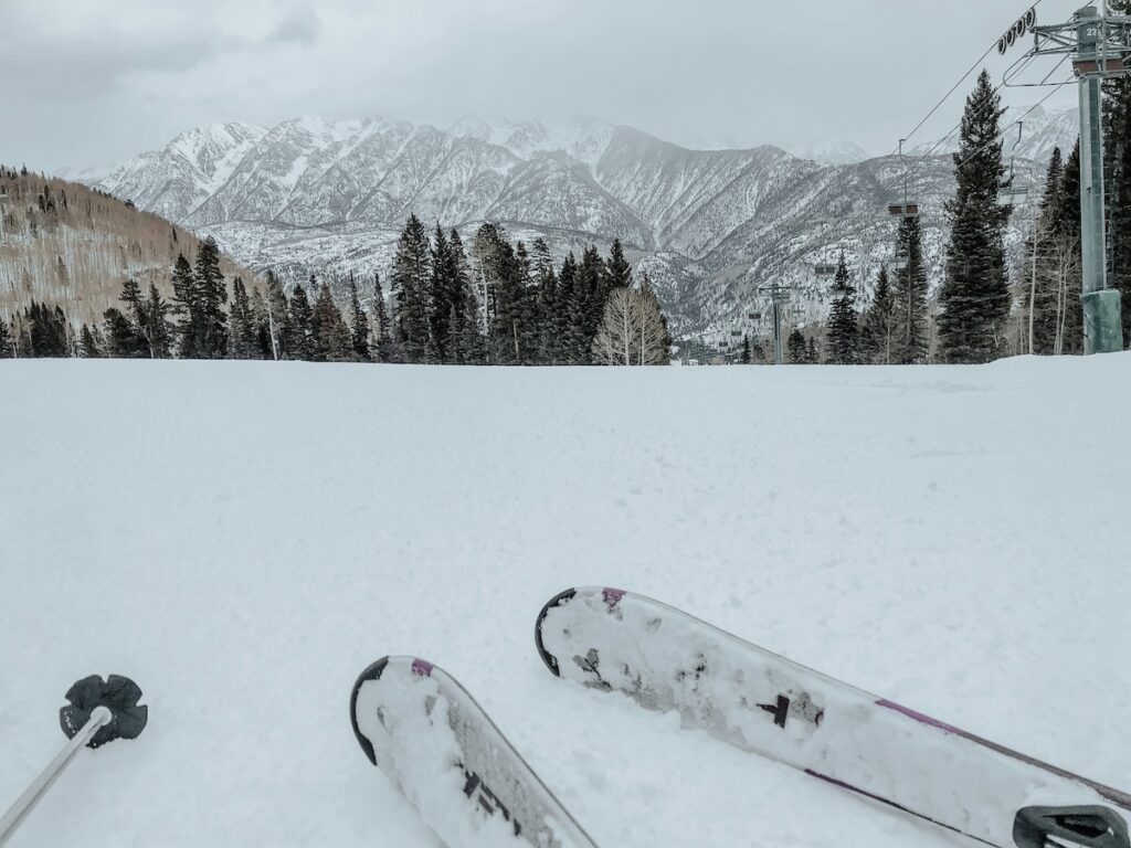 A pair of skis sitting in the snow with cloudy mountains in the background.