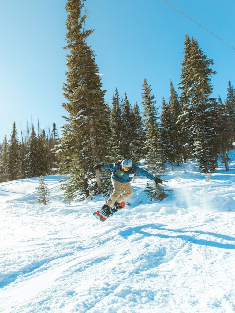A guy jumping on a snowboarder at Wolf Creek.