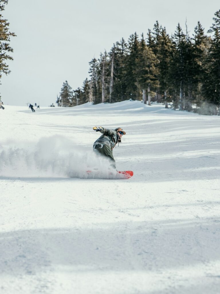 A snowboarder on his edge going fast down a slope.