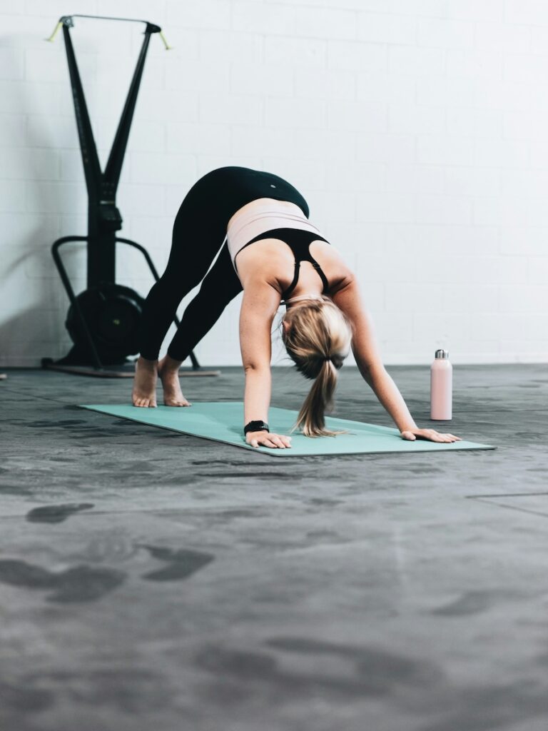 A woman stretching on a yoga mat indoors.