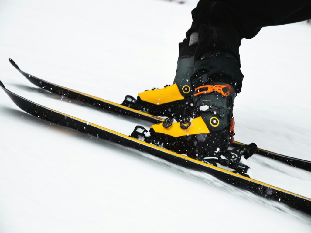 Two pair of yellow ski boots on two yellow skis going down the ski slopes.