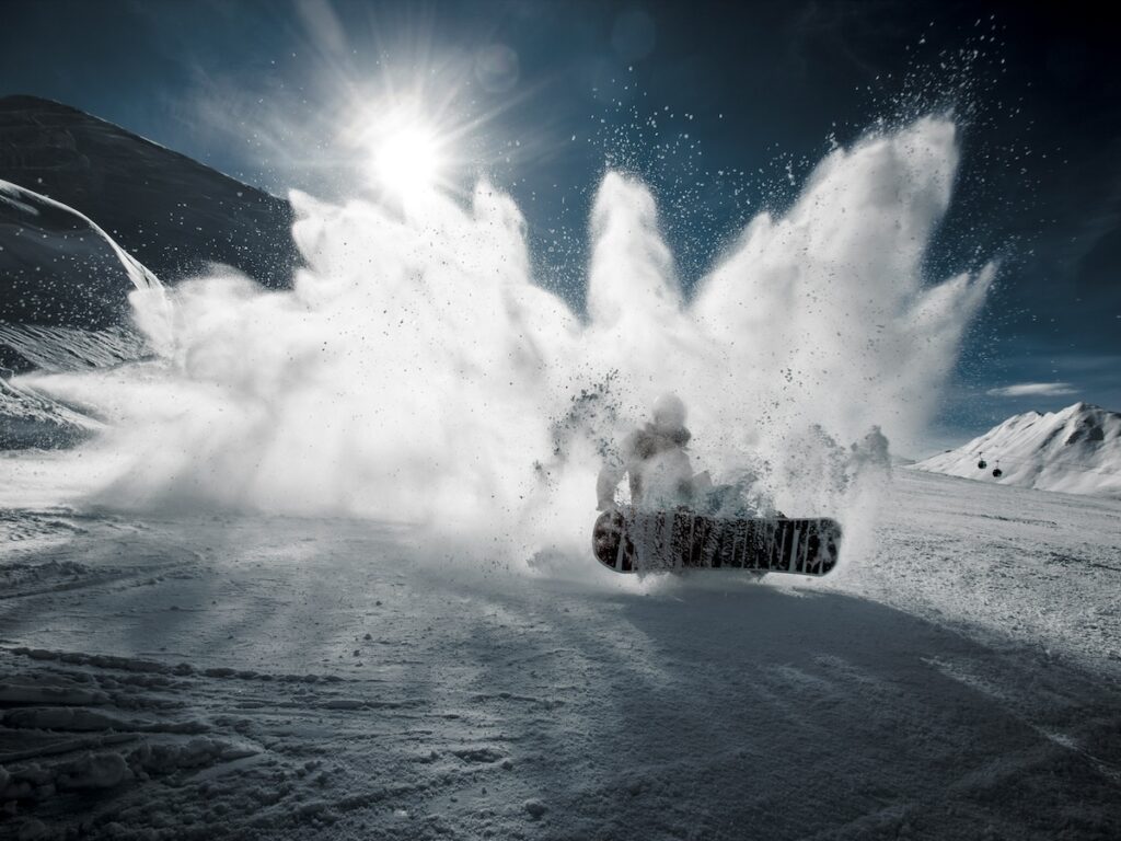 A snowboarder falling on the ski slopes.