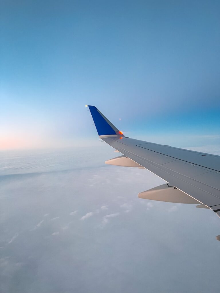 An airplane wing with blue and pink skies.