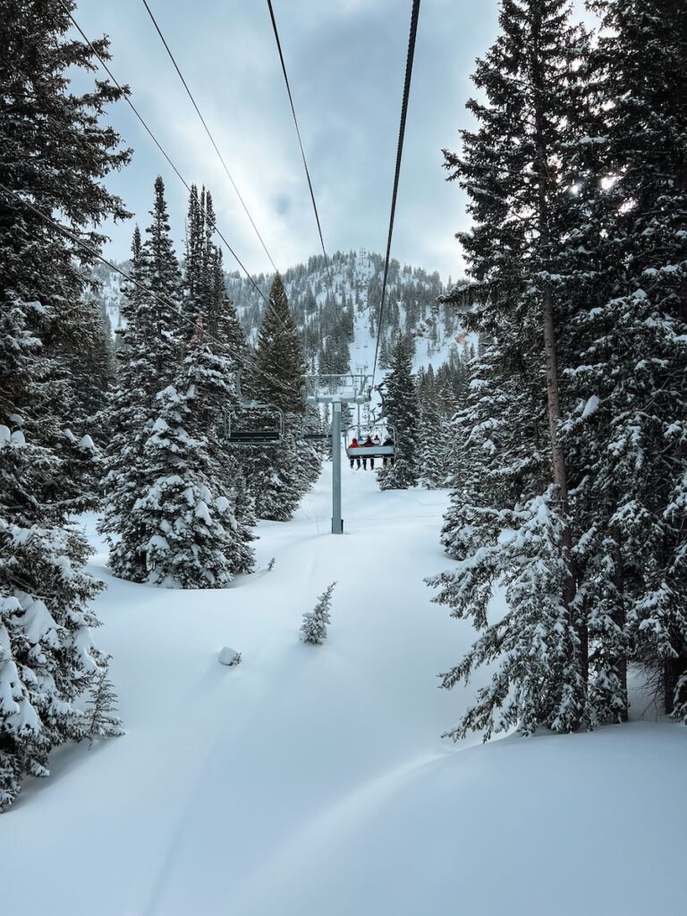 A chair lift in Utah with skiers sitting on it.