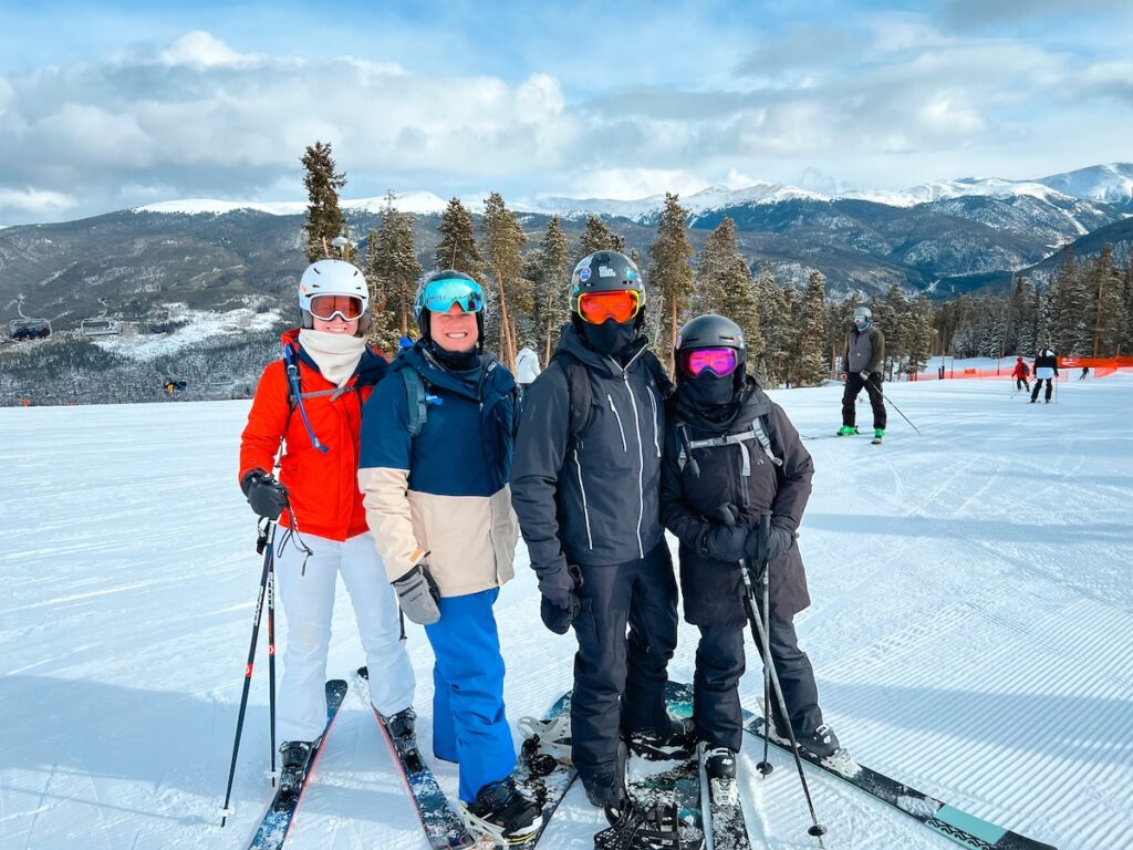 Four friends smiling for a photo on the ski slopes.