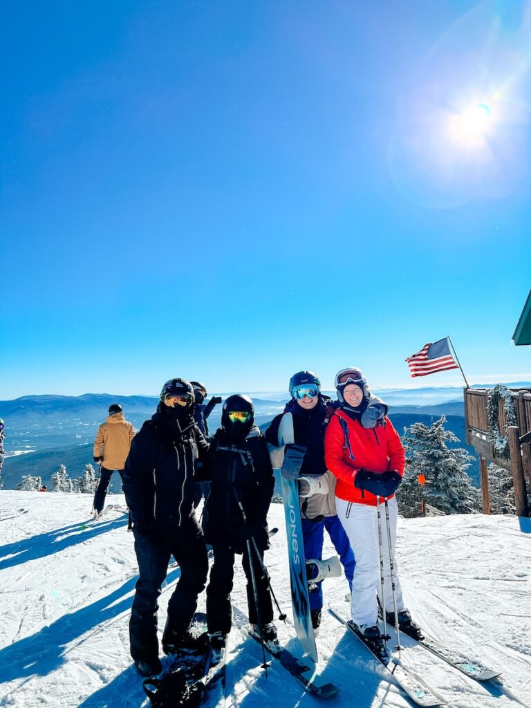 Four friends smiling on the ski slopes in Vermont.