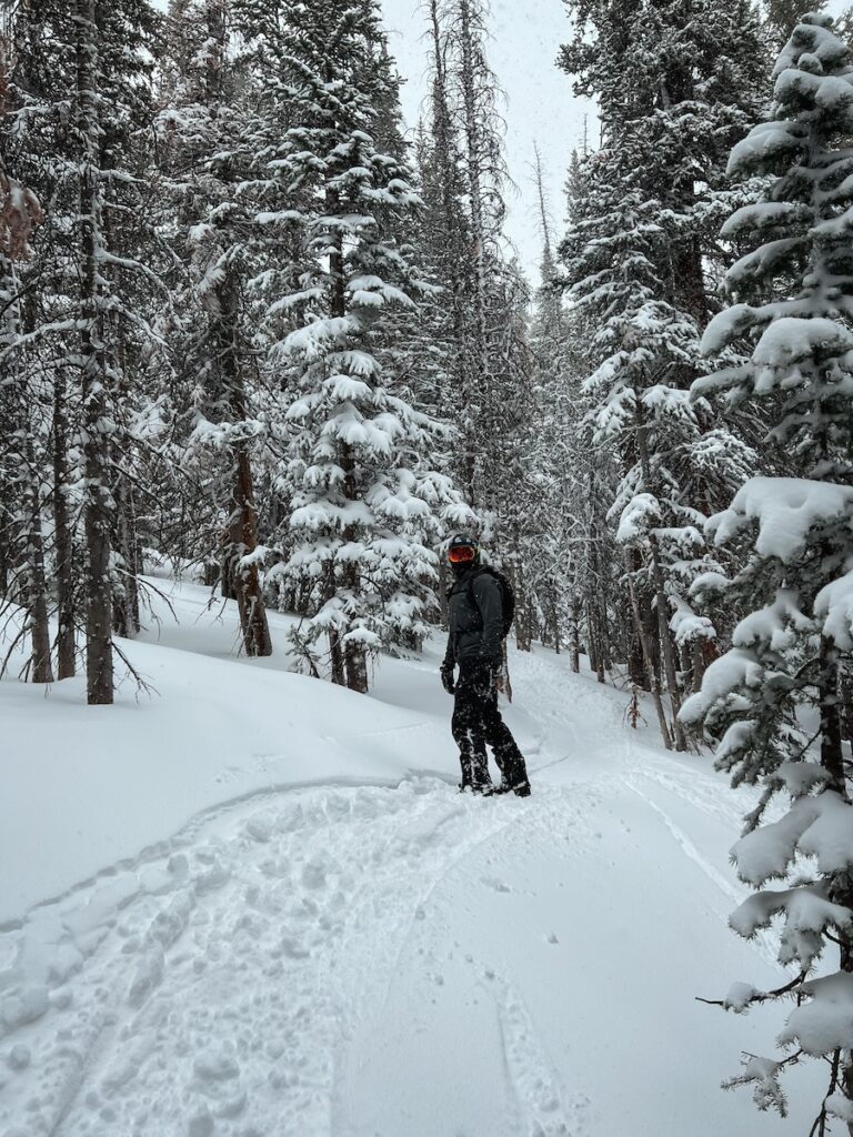 Sam snowboarding through the trees on a powder day at Breck.