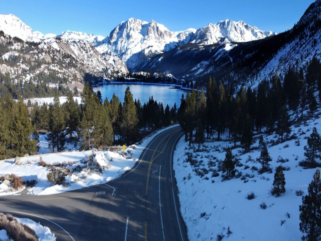 A ski resort in California with a nearby road and lake. 