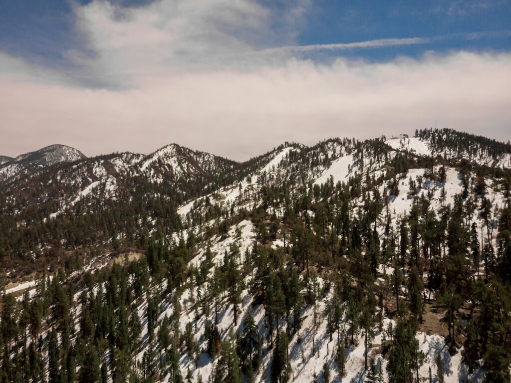 Big Bear, California with snow covered mountains and green trees.