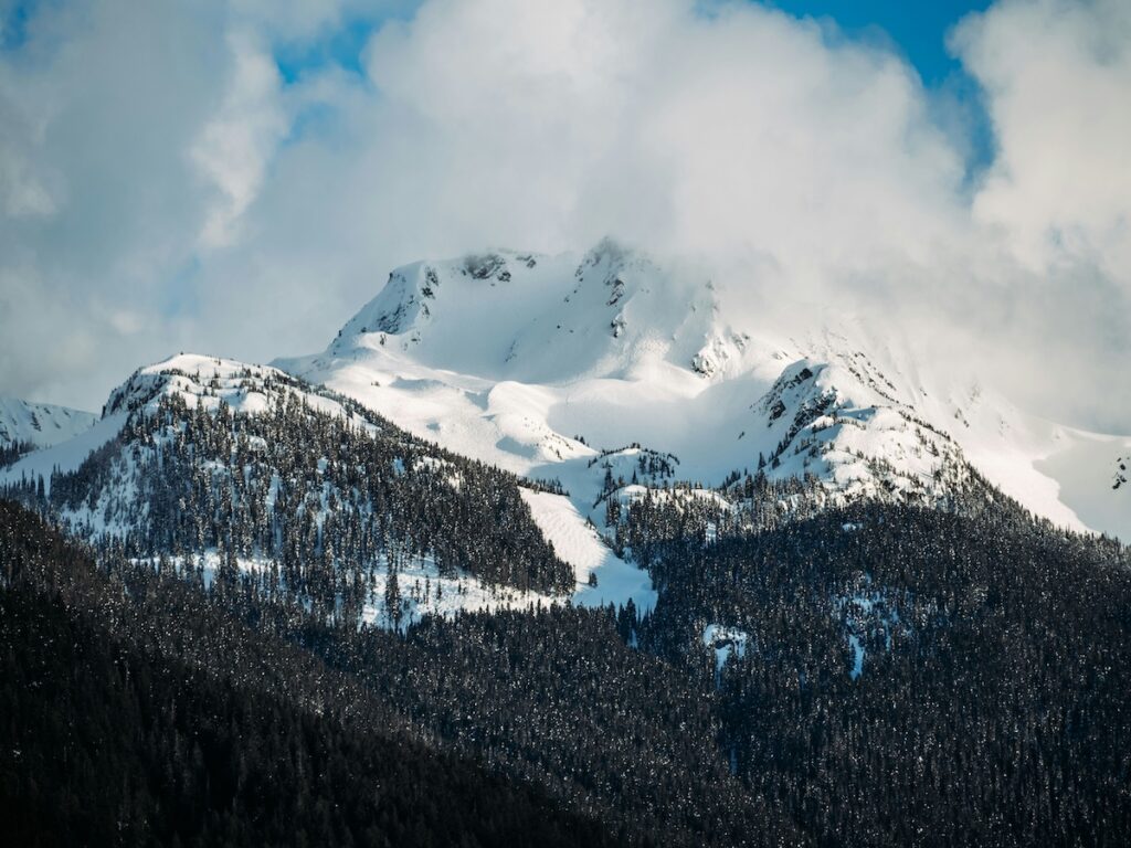 A mountain at Whistler covered in snow with partially cloudy skies.