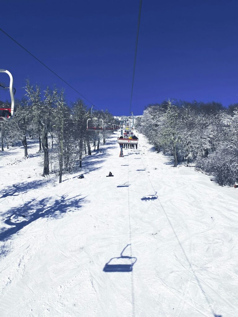 A chair lift and snowy slopes below on a blue sky day in Argentina.