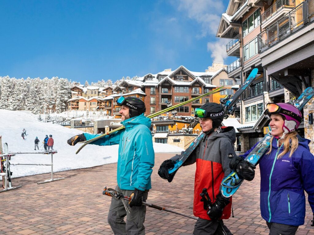 Three skiers walking out to the slopes from the Grand Colorado On Peak 8.