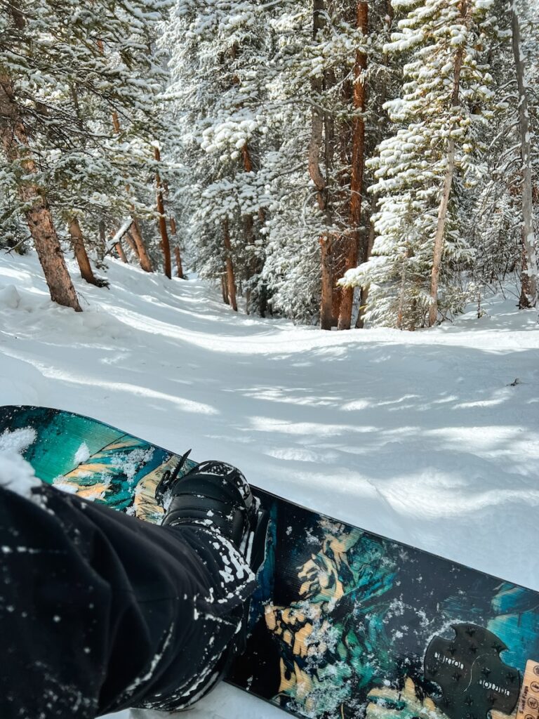 Sam snowboarding through trees.