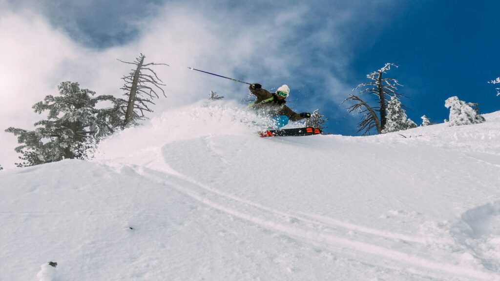 A skier going down a steep slope of powder.