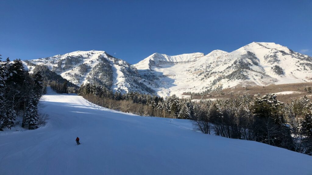 A beautiful bluebird day at a ski resort with snowy mountains off in the distance.