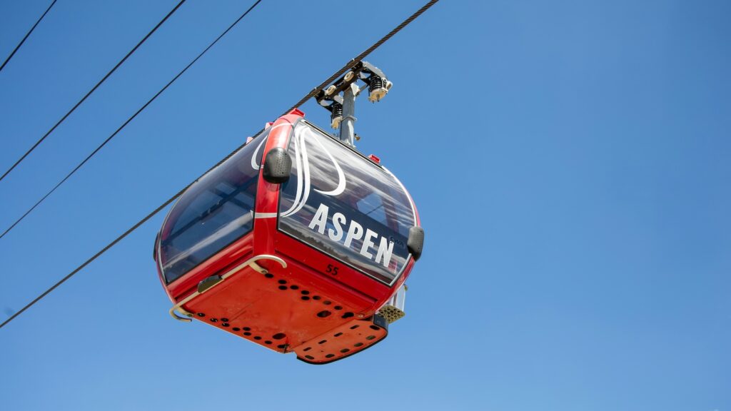 A red gondola at Aspen Mountain with blue skies above.