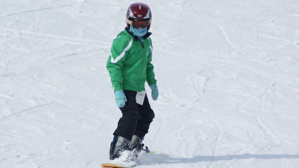 A snowboarder in a green jacket.