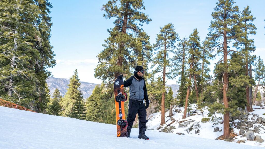 A snowboarder posing with his board at Big Bear.