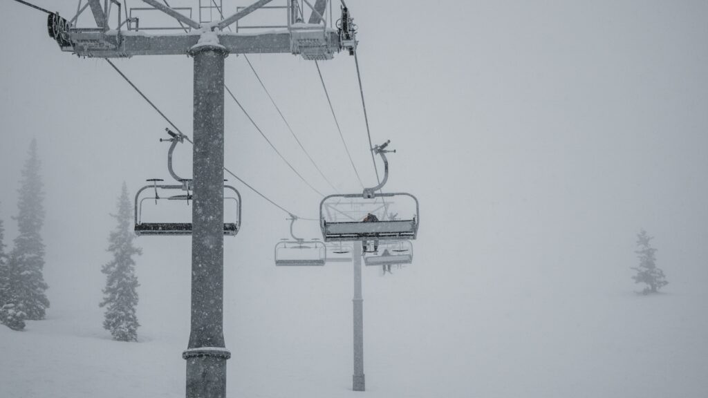 A skier sitting along on a chairlift on a powder day.   