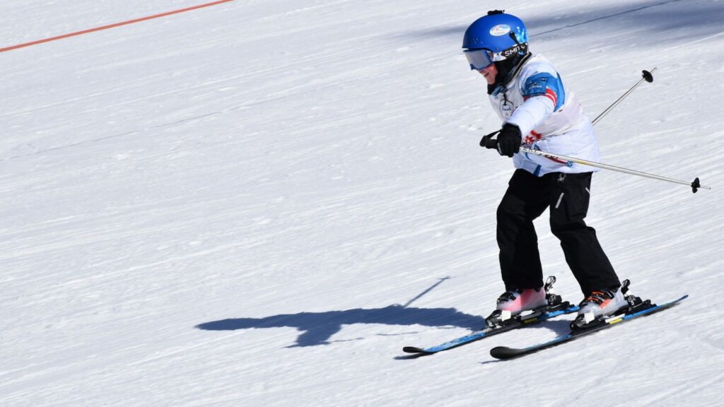 A skier in a white jacket going fast down the mountain.