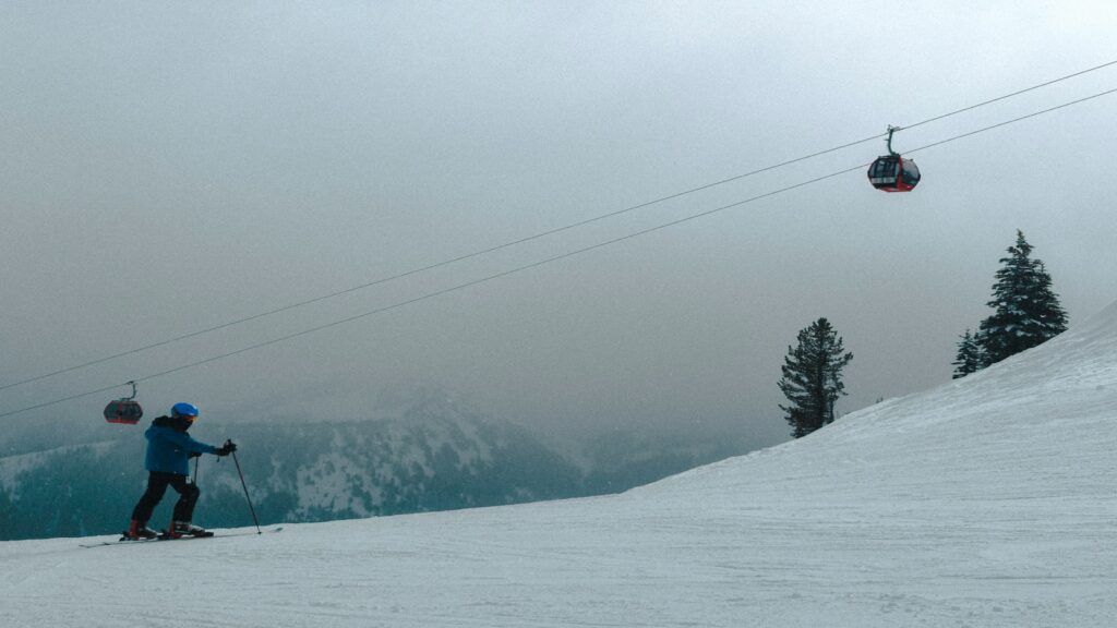 A skier with gondolas passing by in the background on a cloudy day at Crystal Mountain.