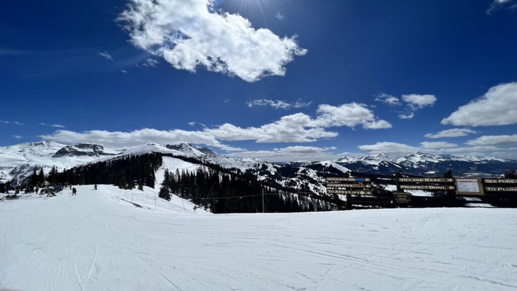 A groomed run at Telluride with ski slope signs.