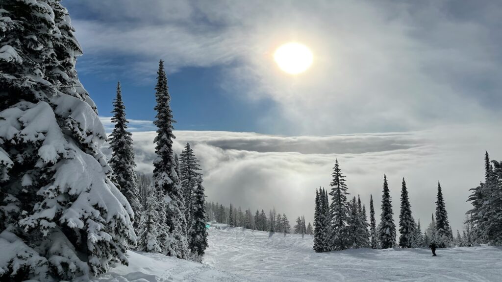 Whitefish, Montana with a mix of clouds and the sun with plenty of snow covered trees surrounding the ski slopes.